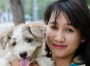 A woman holding a dog with her tongue hanging out.