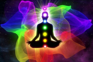 A person sitting in the lotus position with seven chakras on their chest.